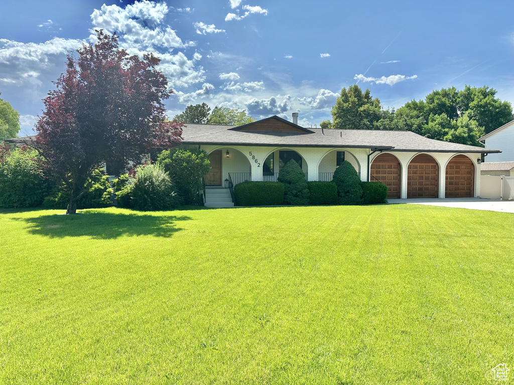 View of front of house featuring a front yard, an attached garage, and concrete driveway