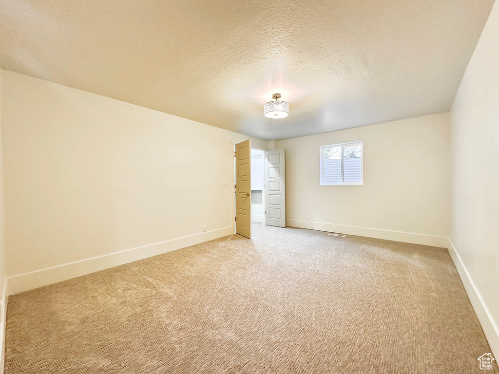 Empty room featuring light colored carpet and a textured ceiling