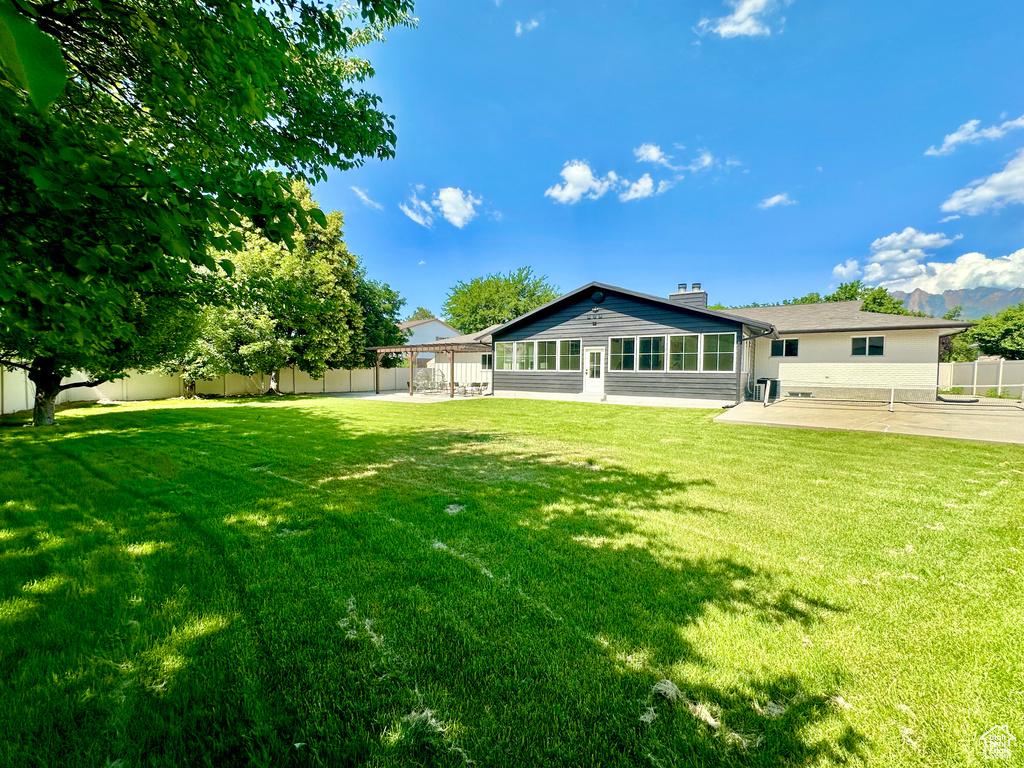 Rear view of property with a patio area, a fenced backyard, a chimney, and a sunroom