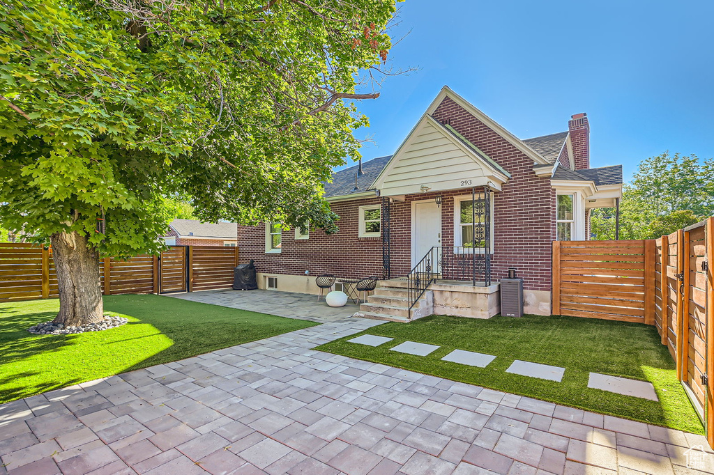 Rear view of property with a chimney, a patio, roof with shingles, and brick siding
