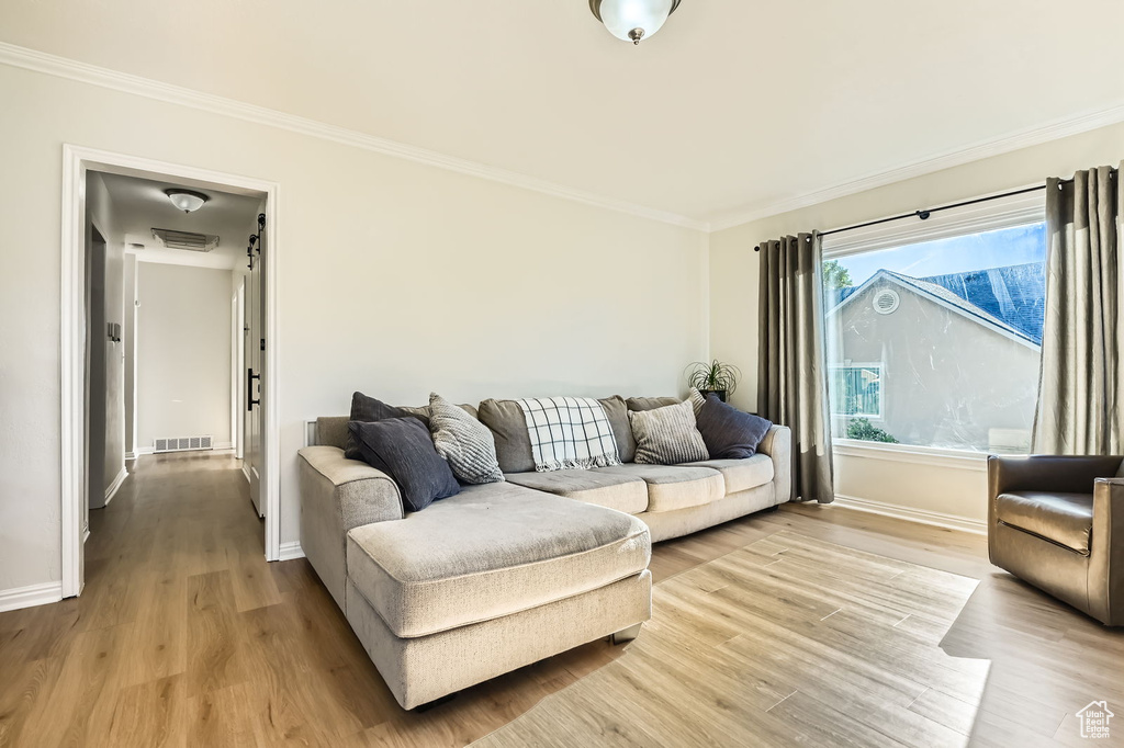 Living area with light wood-style flooring, crown molding, and baseboards