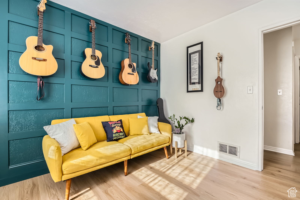 Sitting room featuring wood finished floors, baseboards, and a decorative wall