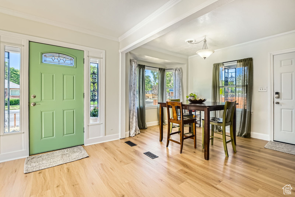 Entryway with light wood-style floors, crown molding, and baseboards