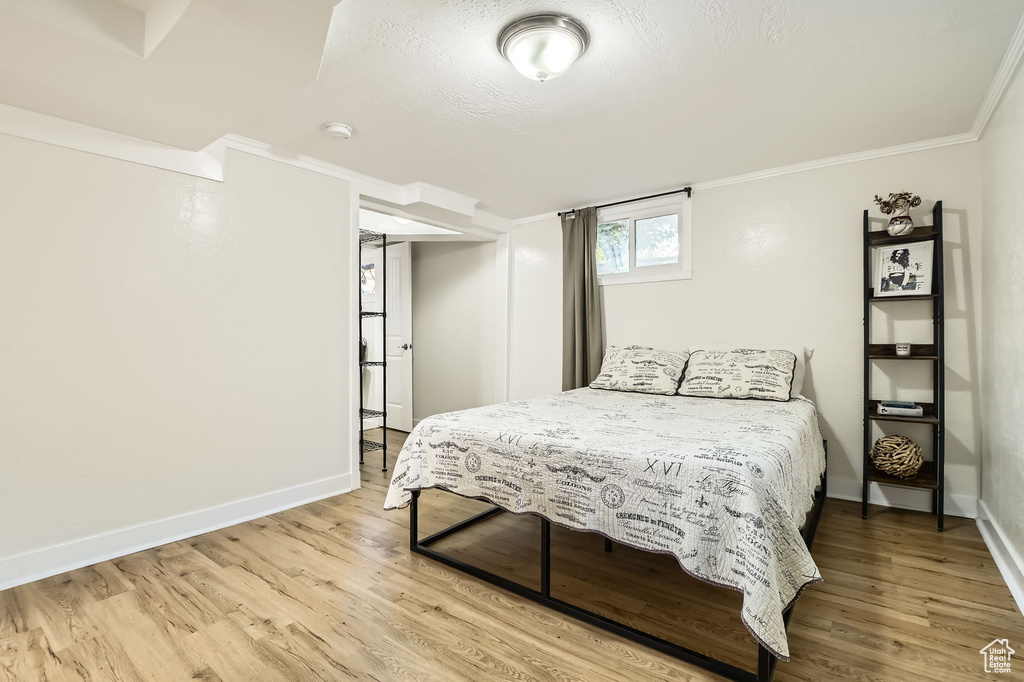 Bedroom with light wood-type flooring, ornamental molding, and baseboards