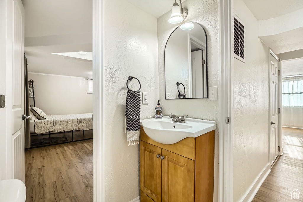 Bathroom with wood finished floors, vanity, connected bathroom, a textured wall, and baseboards