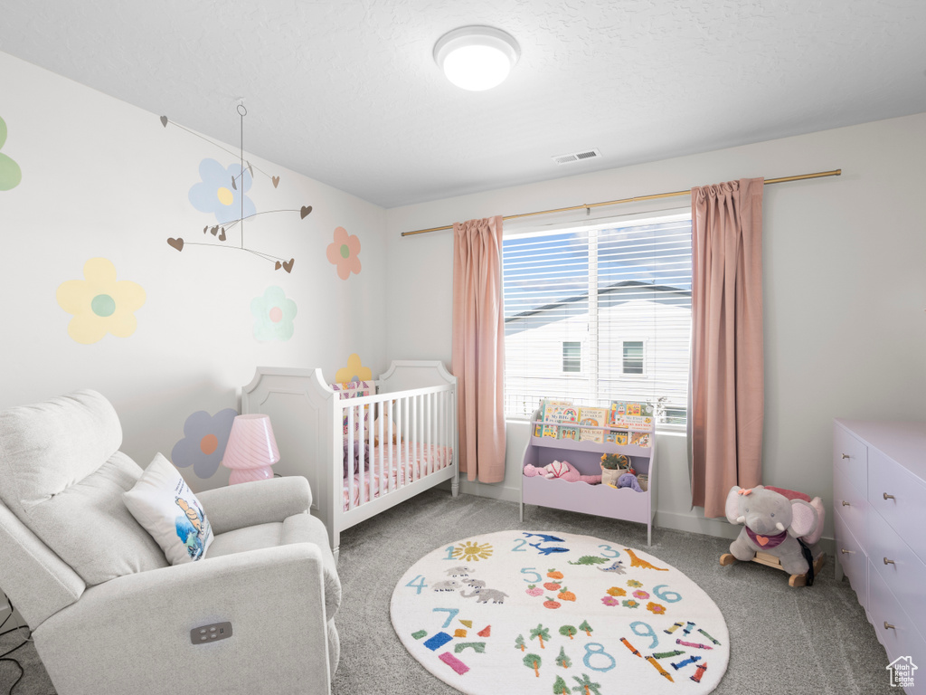Bedroom with a crib and carpet flooring
