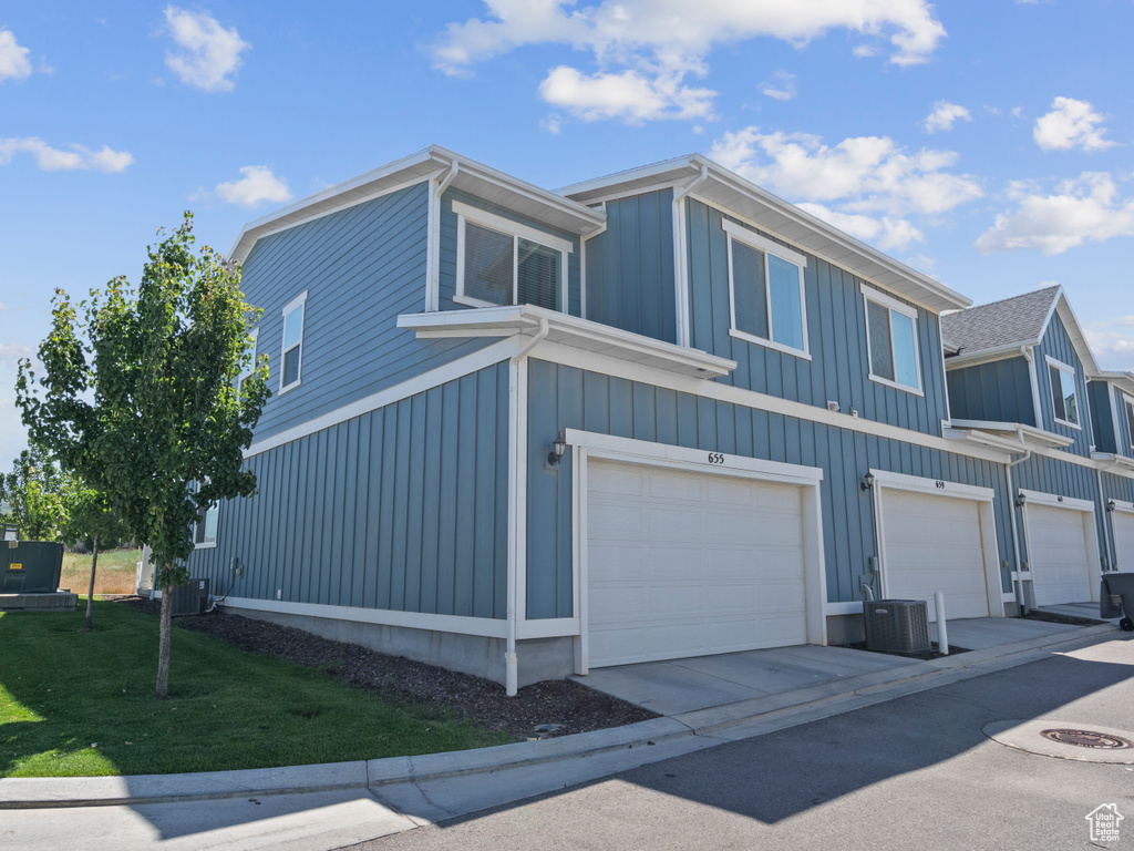 View of home's exterior featuring a garage, board and batten siding, a lawn, and driveway
