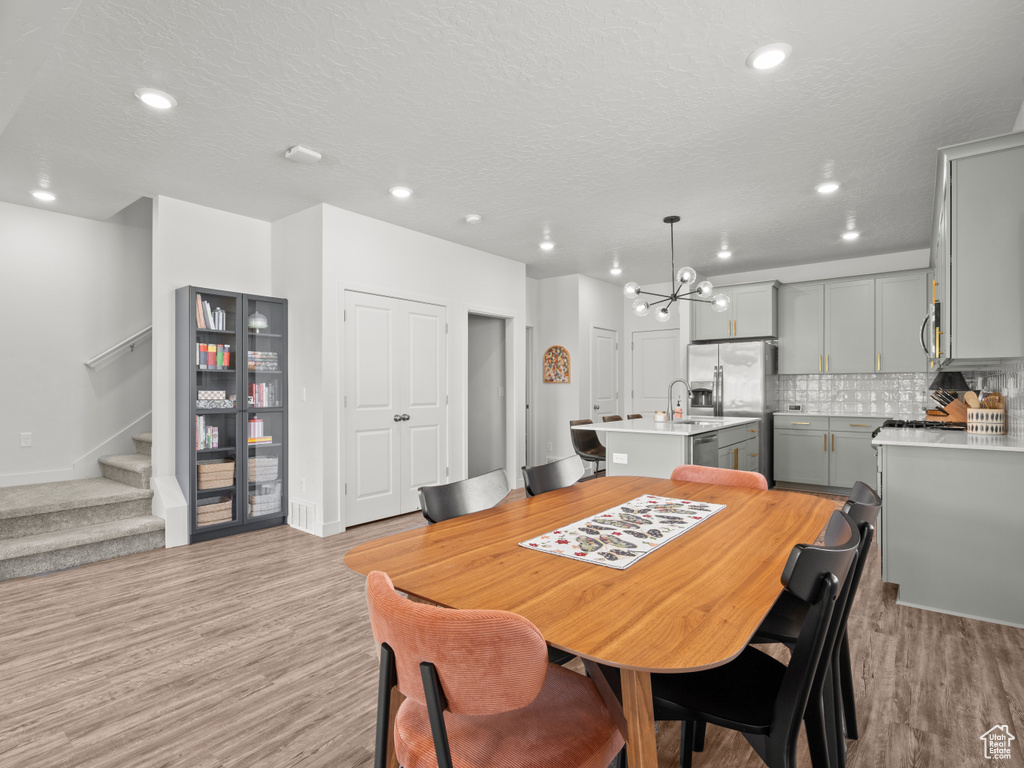Dining room featuring a chandelier, light wood-type flooring, stairway, recessed lighting, and a textured ceiling