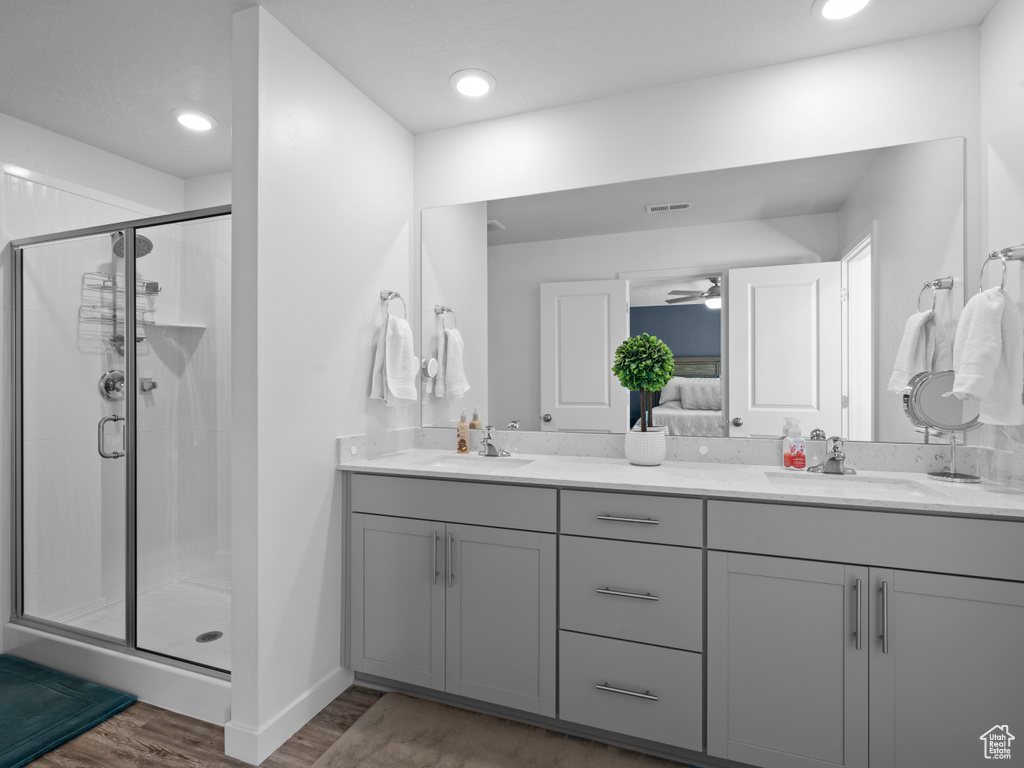 Ensuite bathroom featuring double vanity, a stall shower, wood finished floors, and ceiling fan