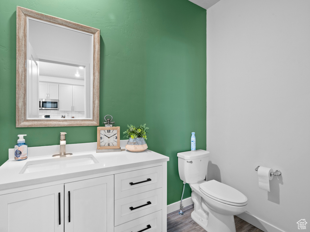 Half bath with vanity and wood finished floors