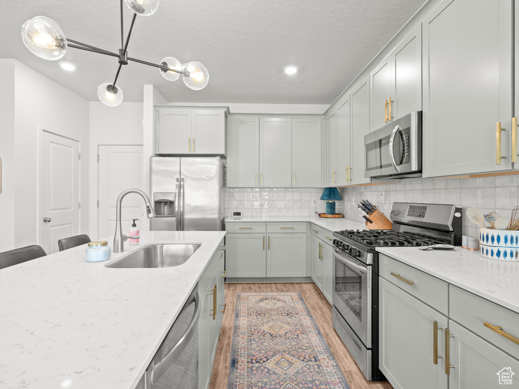 Kitchen with appliances with stainless steel finishes, light wood-style flooring, light stone countertops, decorative backsplash, and recessed lighting