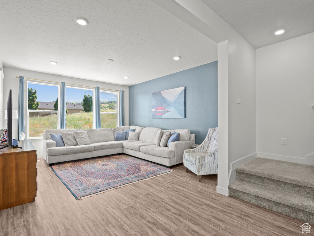 Living room with wood finished floors, recessed lighting, a textured ceiling, and stairway