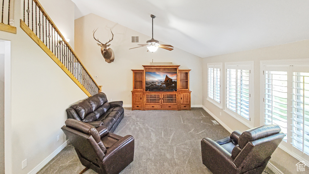 Carpeted living room with a ceiling fan, healthy amount of natural light, vaulted ceiling, and stairs