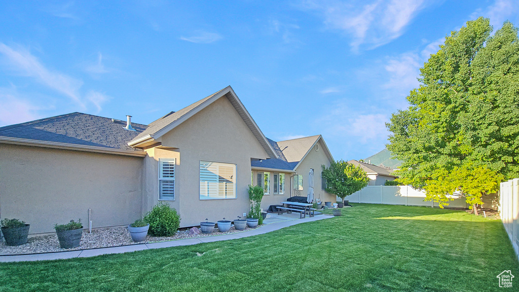 Back of house featuring stucco siding, a fenced backyard, a shingled roof, and a patio