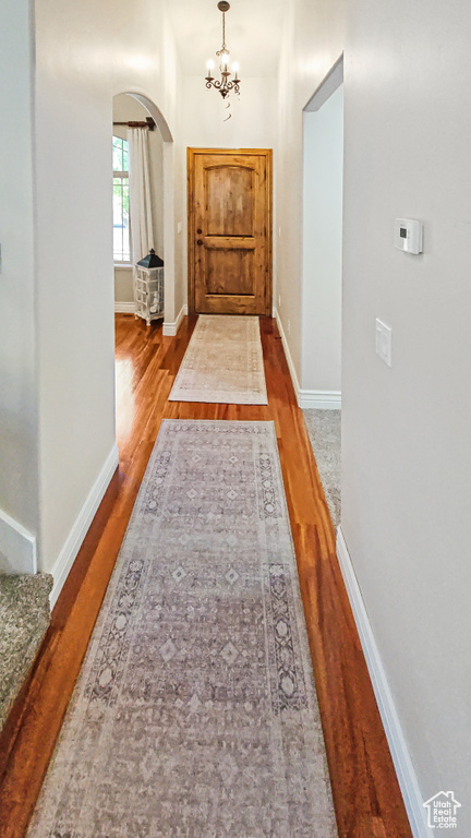 Corridor featuring arched walkways, wood finished floors, and a chandelier