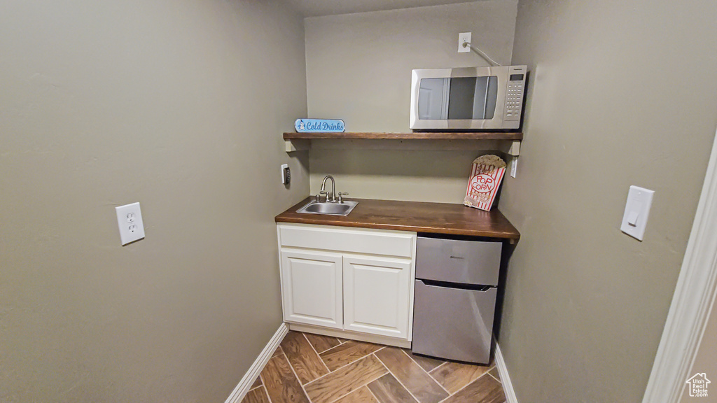 Indoor wet bar featuring stainless steel microwave and refrigerator