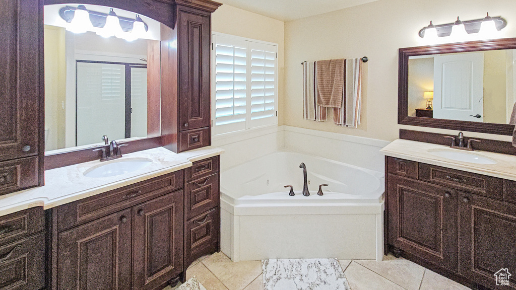 Full bathroom with two vanities, a bath, and tile patterned floors