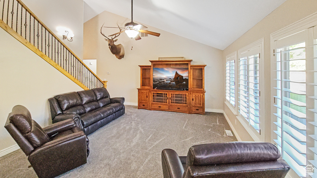 Living area with ceiling fan, carpet floors, healthy amount of natural light, and high vaulted ceiling