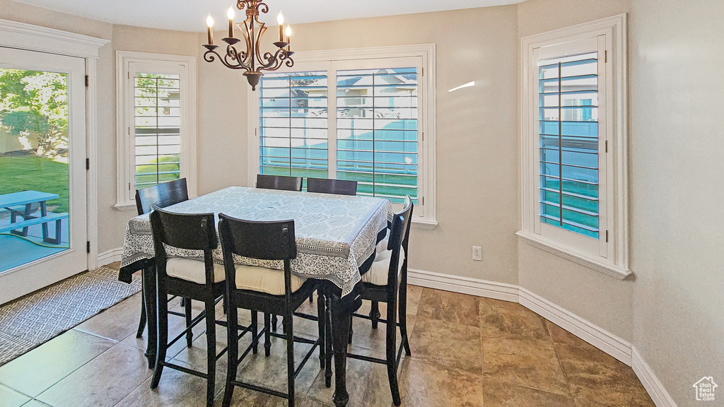 Tiled dining room featuring a chandelier and baseboards
