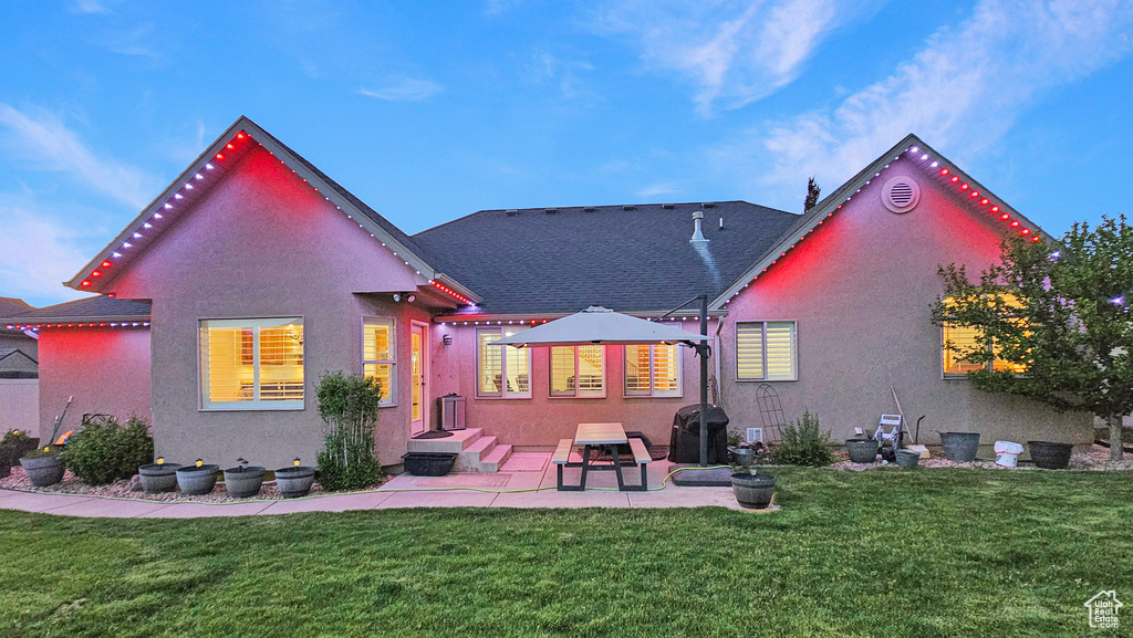 Rear view of house with stucco siding, a lawn, and a patio area