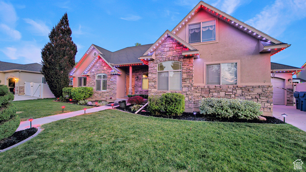View of front of house featuring stone siding, stucco siding, and a gate