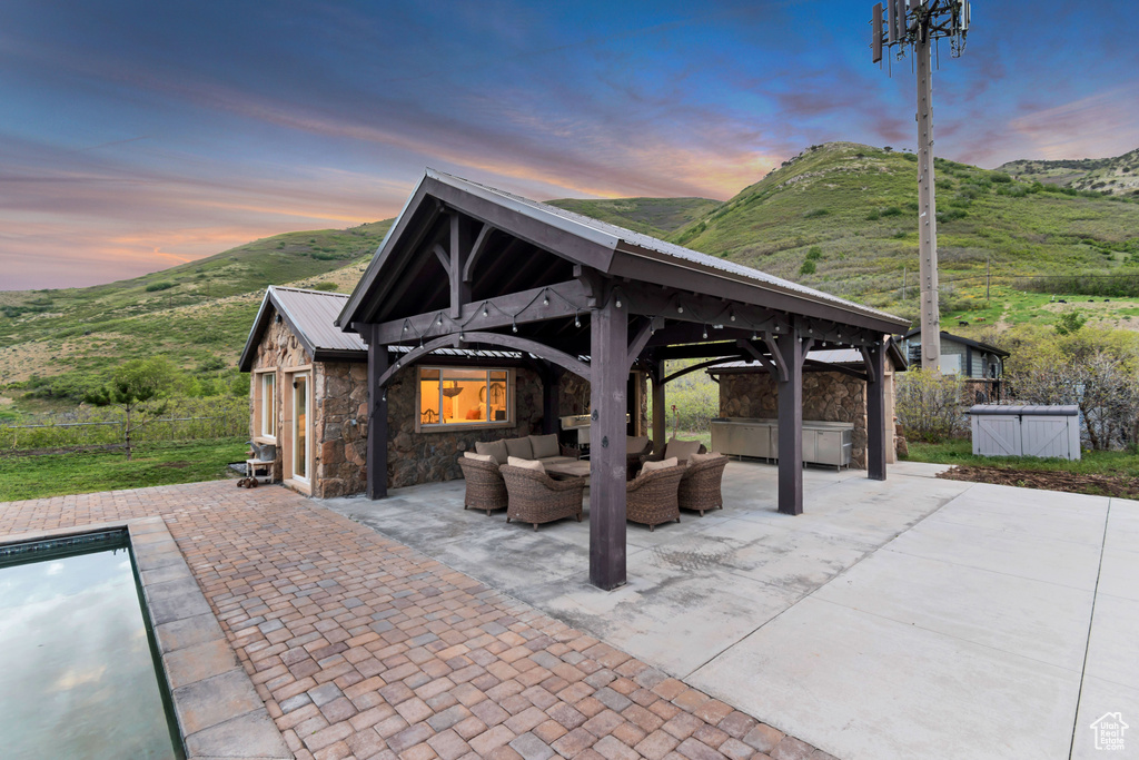 Patio terrace at dusk featuring an outdoor living space, a gazebo, a hot tub, and a mountain view