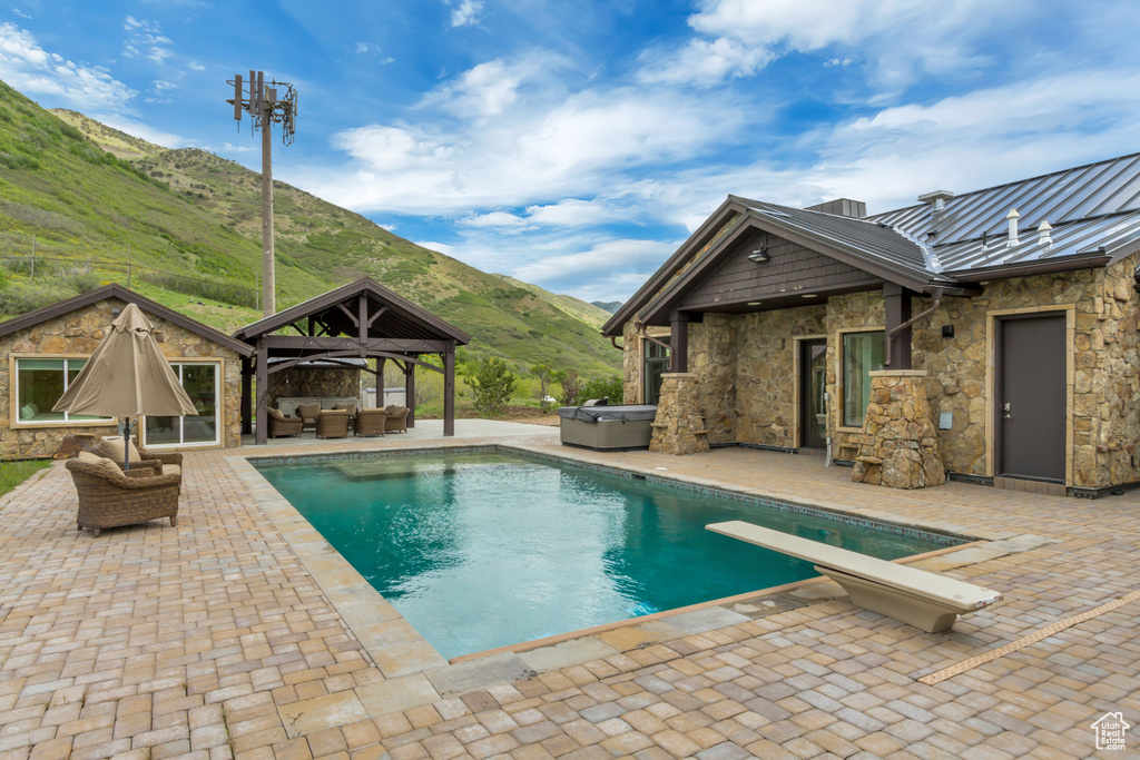 Outdoor pool with an outdoor living space, a gazebo, a mountain view, a patio area, and a hot tub