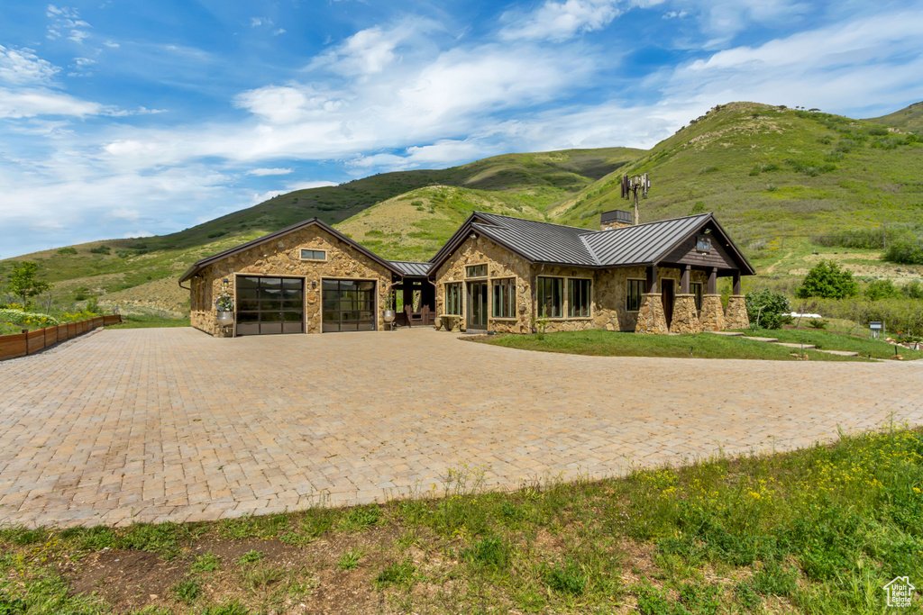 View of front facade featuring a standing seam roof, stone siding, a mountain view, and metal roof