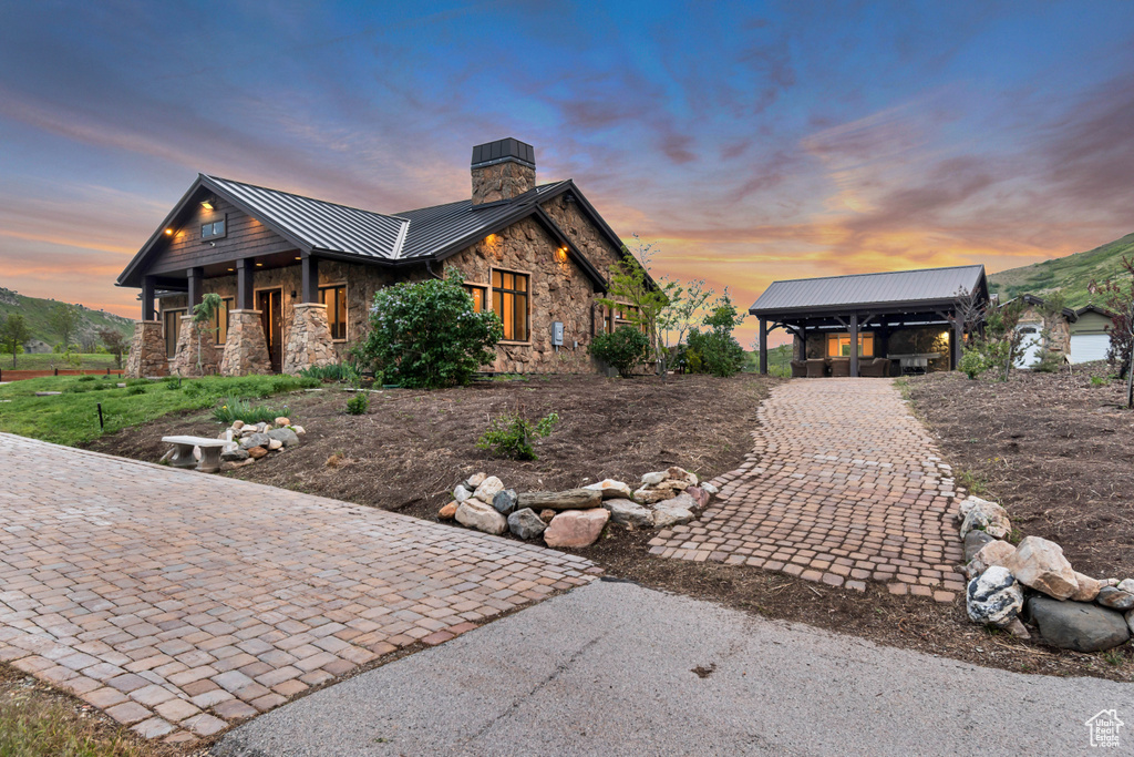 View of front of property with a standing seam roof, stone siding, a chimney, and metal roof
