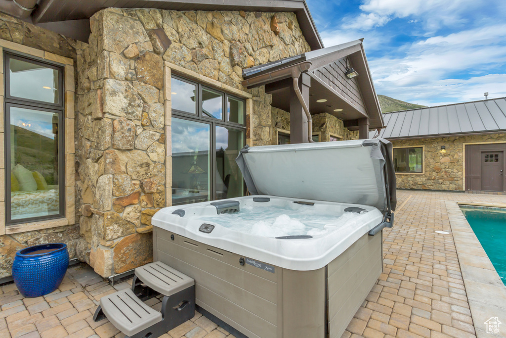 View of patio / terrace with a hot tub and a pool