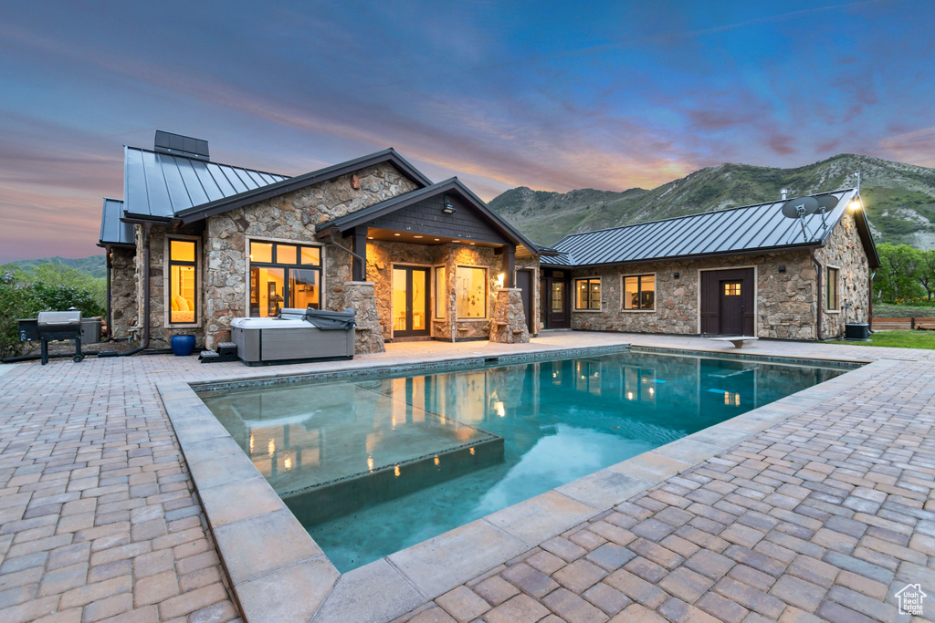 Pool at dusk with a patio, an outdoor pool, grilling area, and a mountain view