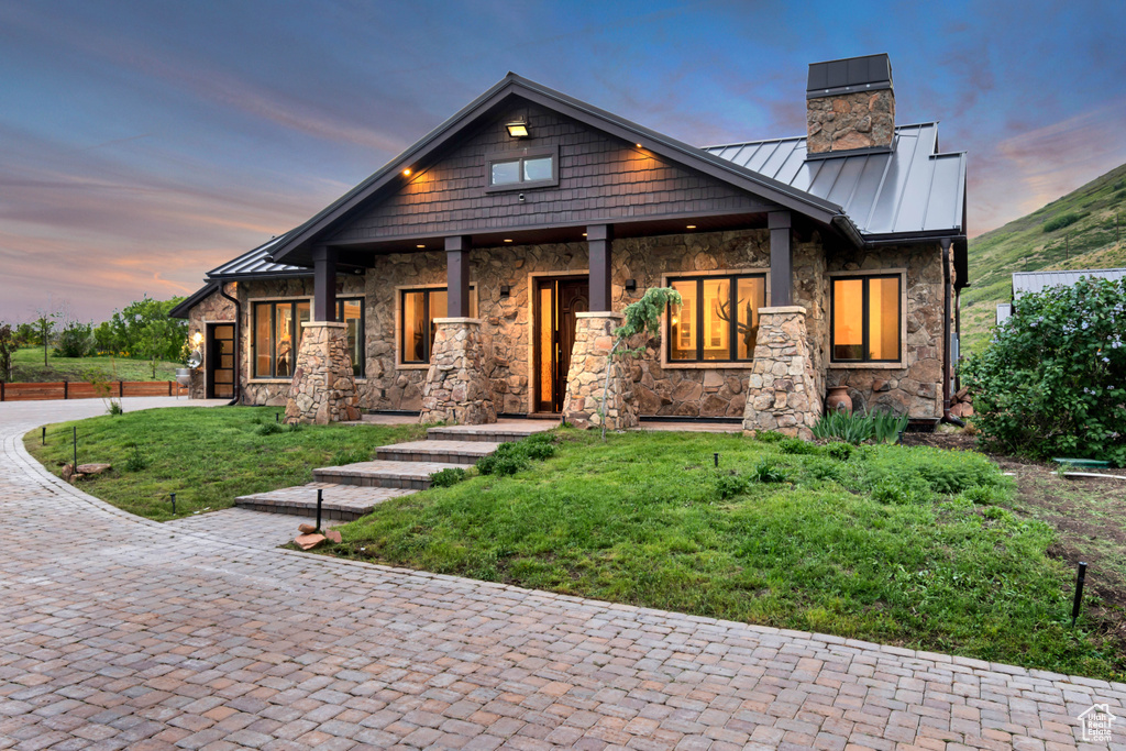 Craftsman house with a standing seam roof, a chimney, stone siding, metal roof, and a front yard