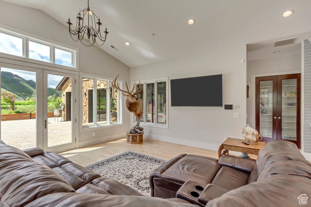 Living area with french doors, a chandelier, wood finished floors, recessed lighting, and high vaulted ceiling