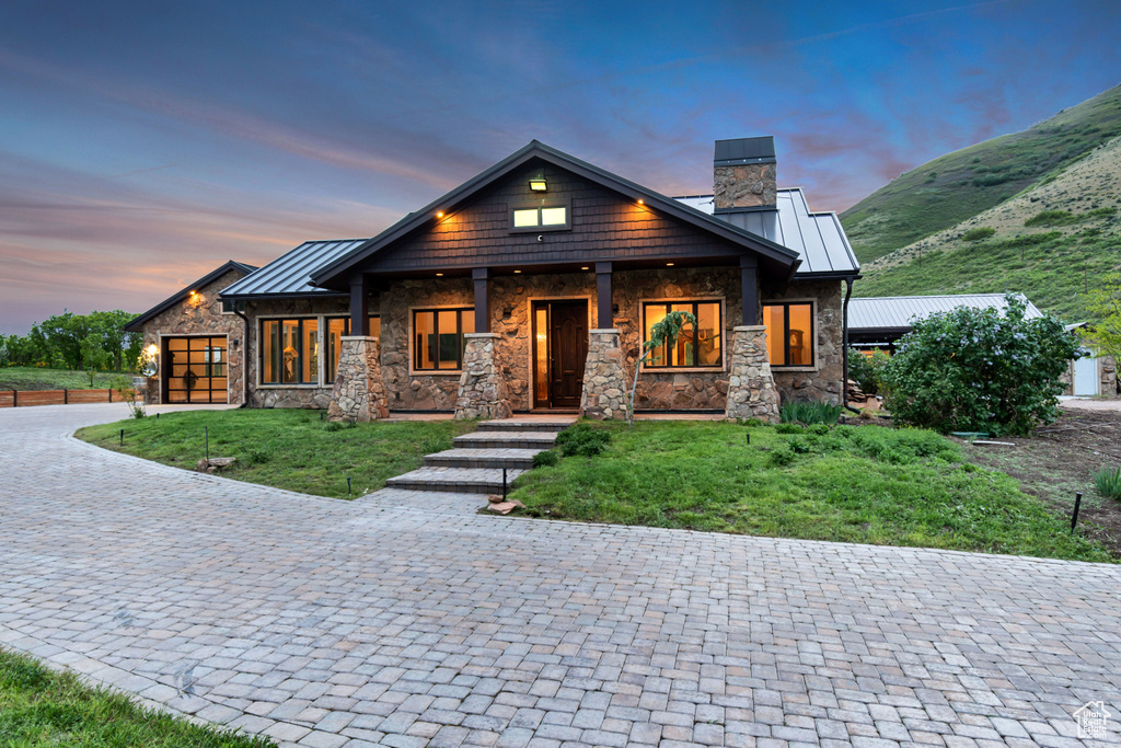 View of front of home with stone siding, a standing seam roof, and a chimney