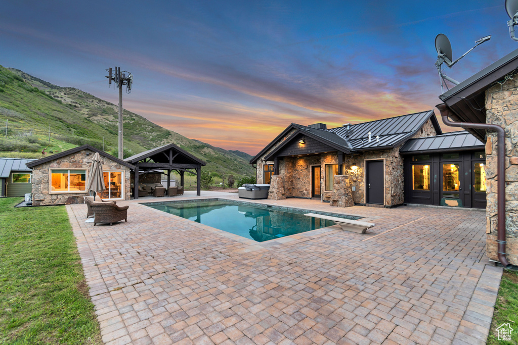 Outdoor pool with a patio area, a mountain view, outdoor lounge area, a gazebo, and an outbuilding
