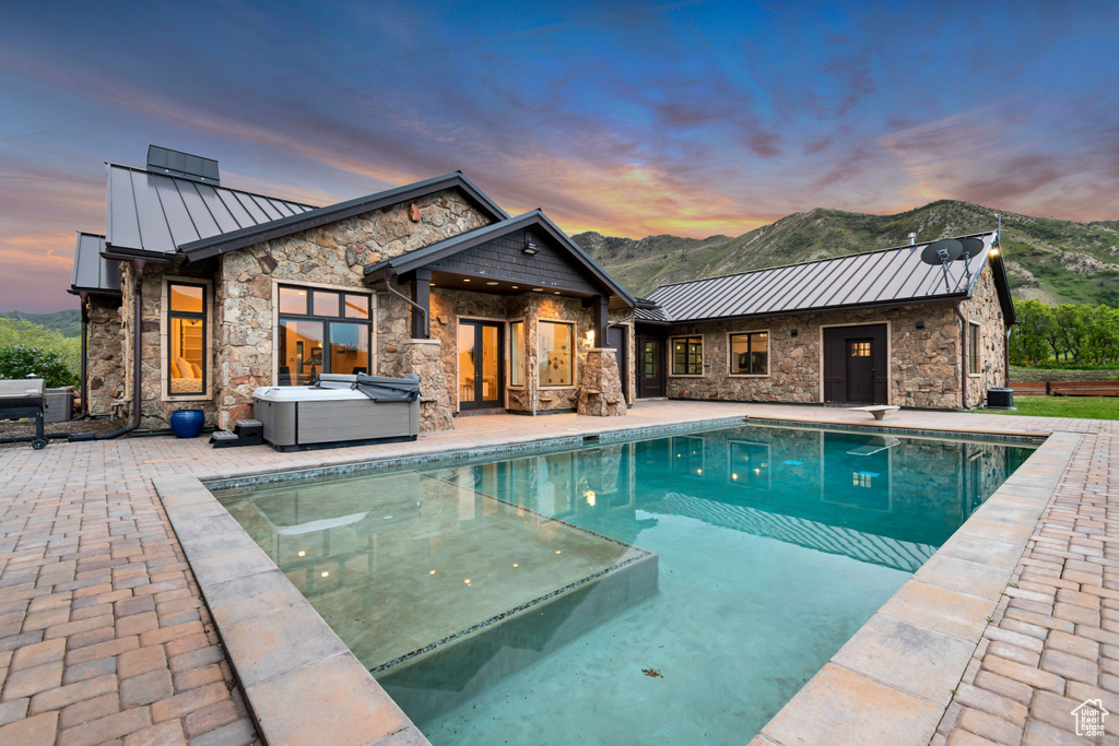Outdoor pool with a hot tub, a patio area, and a mountain view