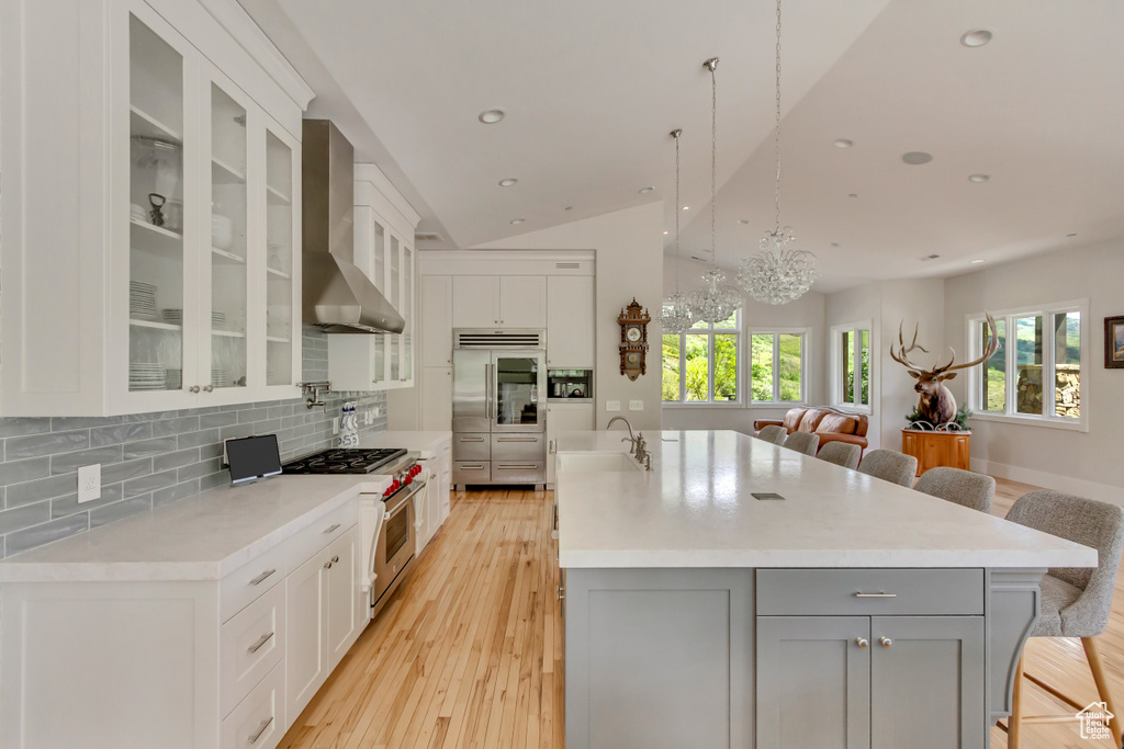 Kitchen featuring high quality appliances, a sink, gray cabinetry, a breakfast bar area, and vaulted ceiling