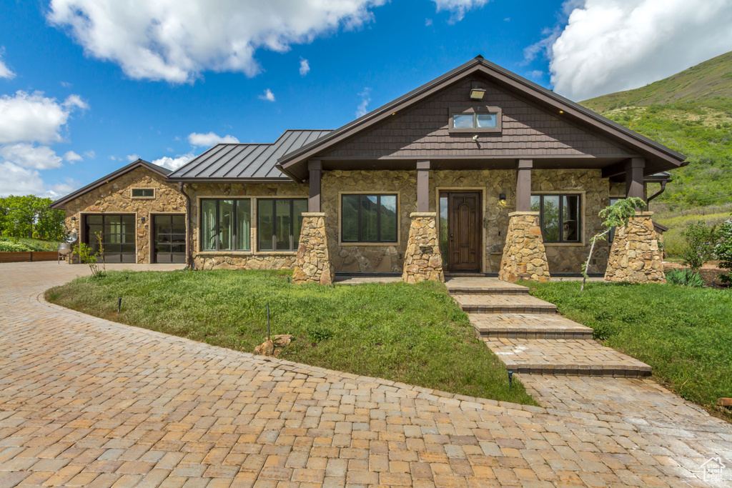 Craftsman inspired home with stone siding, a standing seam roof, a front lawn, and metal roof