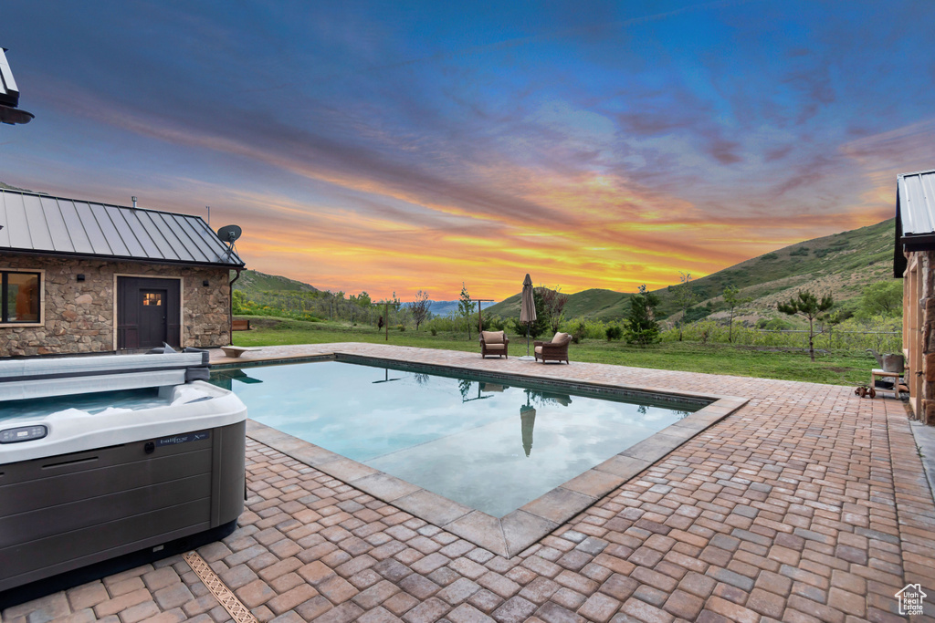 Swimming pool with a patio, a mountain view, and a hot tub