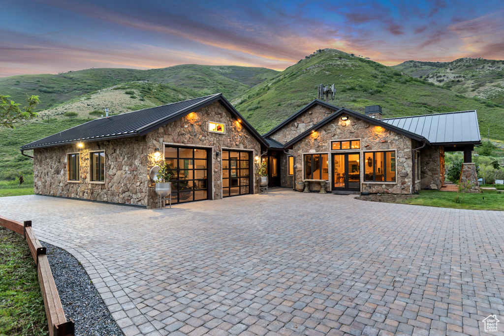 View of front of property with stone siding, a standing seam roof, a garage, metal roof, and a mountain view