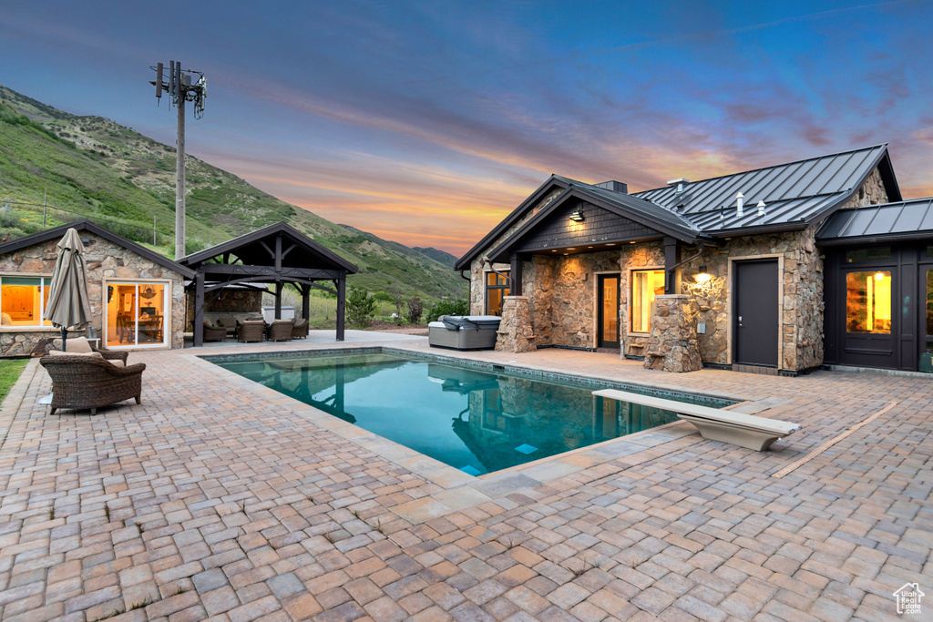 Swimming pool featuring a hot tub, an outdoor living space, a gazebo, a patio area, and a mountain view