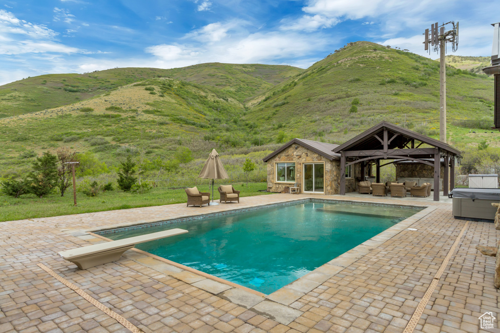 Swimming pool featuring an outdoor hangout area, a patio, a hot tub, a gazebo, and a diving board