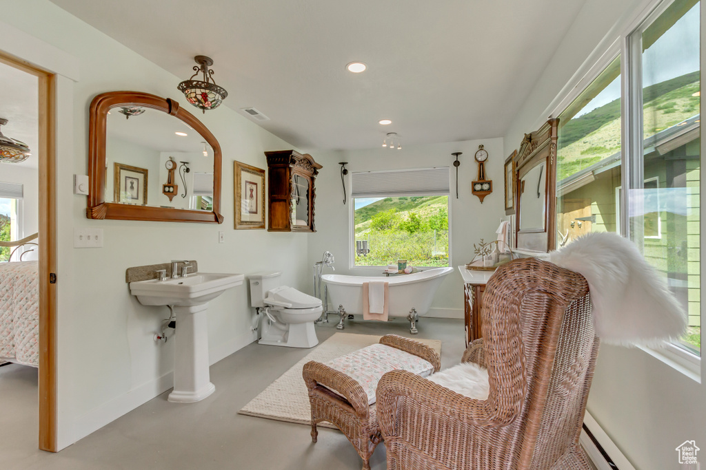 Bathroom with concrete floors, a soaking tub, baseboards, recessed lighting, and a baseboard heating unit