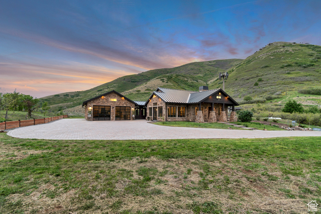 View of front of property featuring stone siding, curved driveway, a mountain view, a standing seam roof, and a chimney