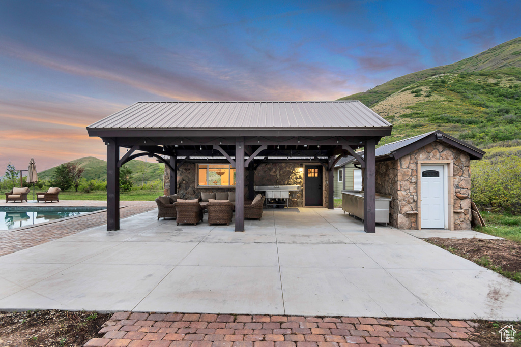 Patio terrace at dusk featuring a gazebo, outdoor lounge area, an outdoor pool, and a mountain view