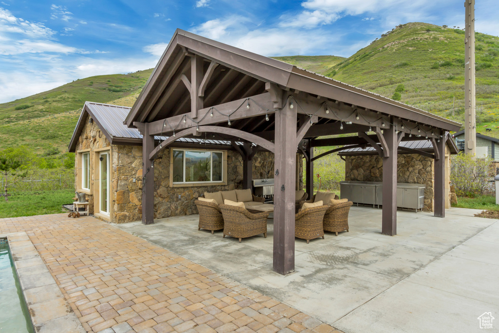 View of patio featuring a hot tub, a gazebo, an outdoor living space, and a mountain view
