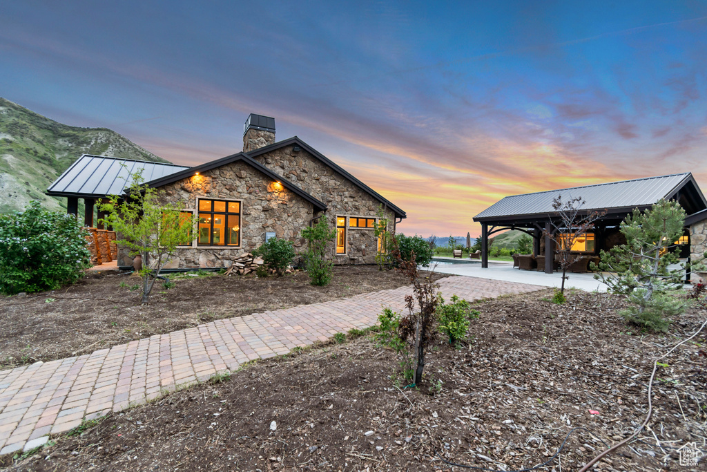View of side of property with a chimney, stone siding, metal roof, and a standing seam roof