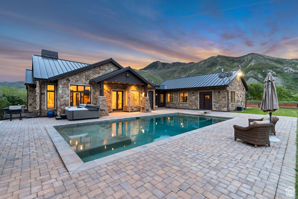 Pool at dusk with a patio, an outdoor living space, a mountain view, an outdoor pool, and a diving board