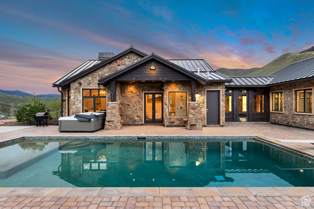 Rear view of house with a standing seam roof, a patio area, french doors, an outdoor pool, and metal roof
