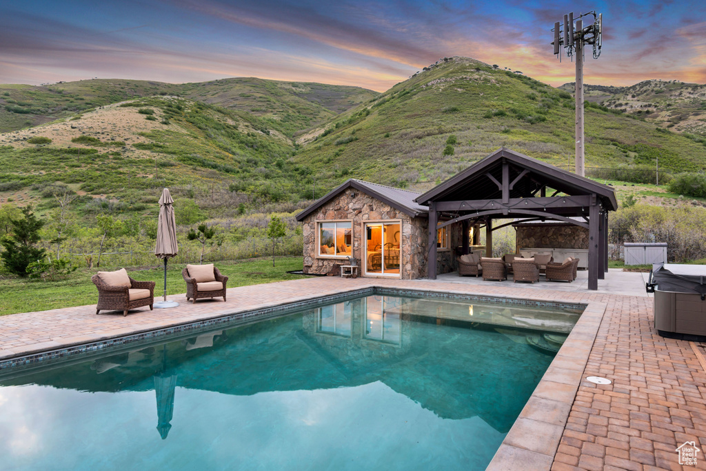 Outdoor pool with outdoor lounge area, a storage structure, an outbuilding, a patio area, and a mountain view